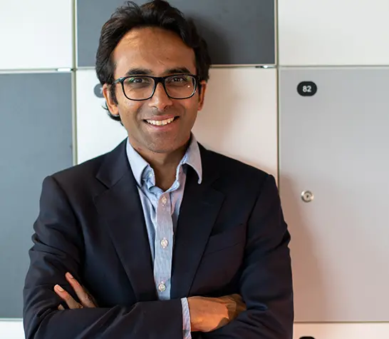 Ravi Gupta with his arms crossed, wearing a dark jacket and light shirt, smiling