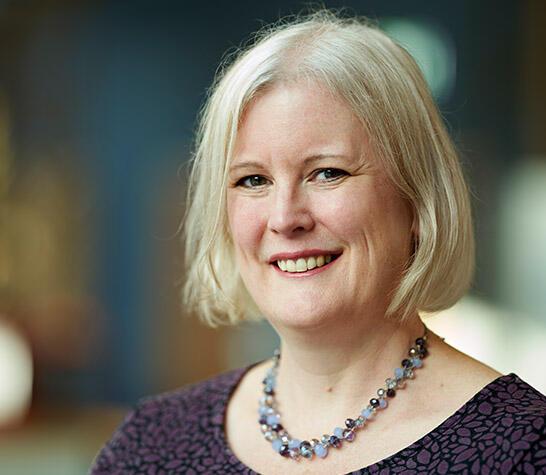 Catherine Noakes with a short blond bob haircut and a chunky necklace smiling