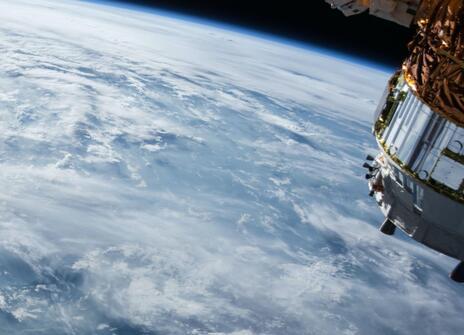 The earth from a distance, with a spaceship satelite coming towards it 