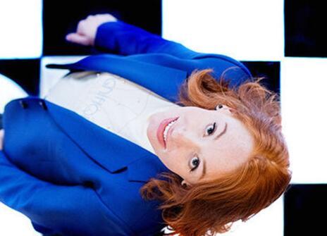 Hannah Fry in a blue suit looking up, standing in a chequered floor