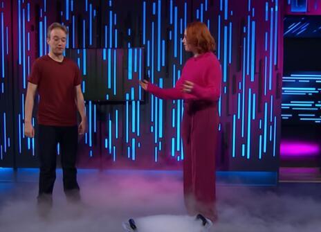 Hannah Fry and a Tom Scott in the Ri lecture theatre, the floor is covered in a thick mist 