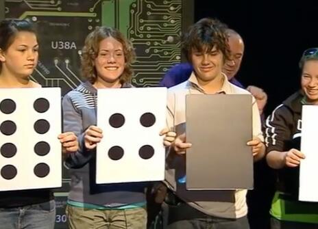 Four children holding up signs that have the pattern of dominoes