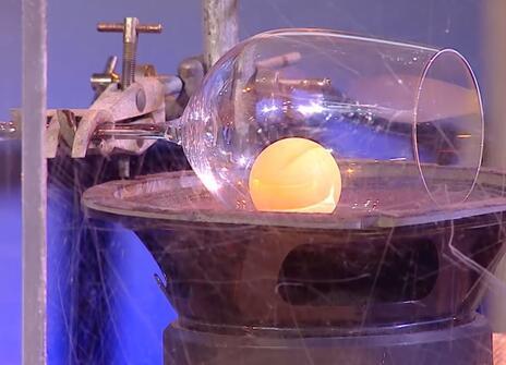 A wine glass tipped on its side with a ping pong ball inside it 
