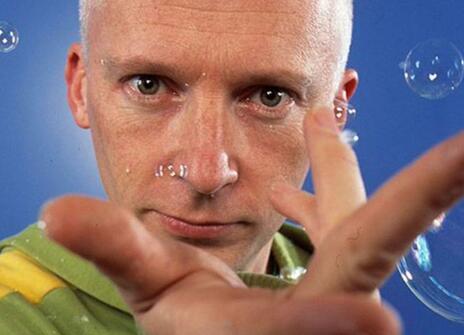 Marcus du Sautoy holding his hand out, with bubbles floating around him