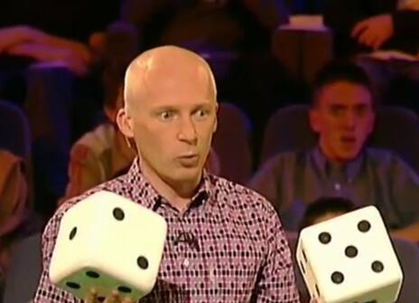 Marcus du Sautoy holding two large dice, standing in front of a crowd