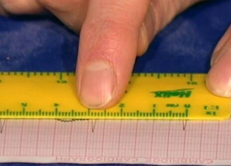 A yellow ruler being used on graph paper