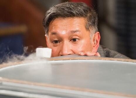 Saiful Islam looking over a cannister which gas is pouring out of