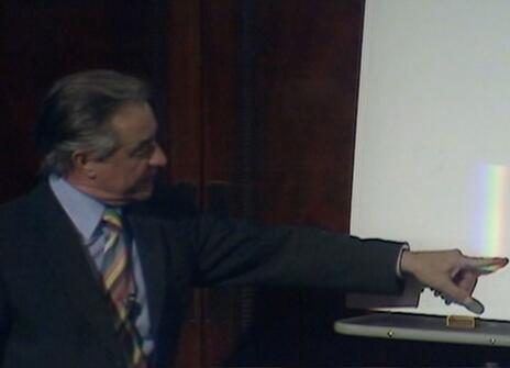 George Porter pointing at a rainbow beam of light on a white screen