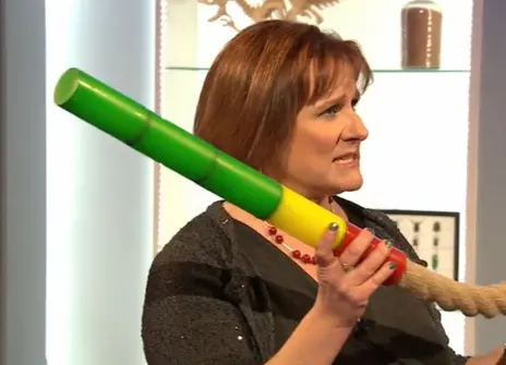 Alison Woollard holding a length of rope, which has a rainbow coloured nozzle attached to it 