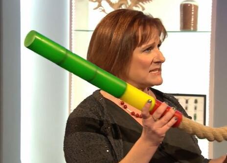 Alison Woollard holding a length of rope, which has a rainbow coloured nozzle attached to it 