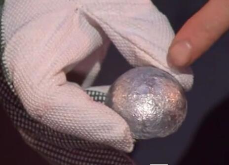 a white-gloved hand holding a silver dome of metal