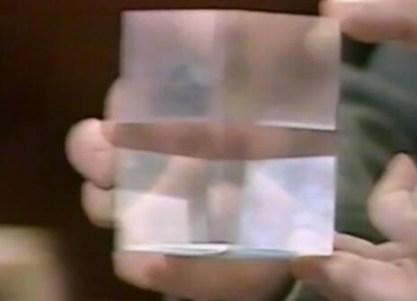 A close up of a man holding a clear cube