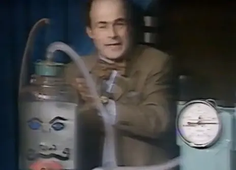 Heinz Wolff standing next to a contraption with a drawn-on face