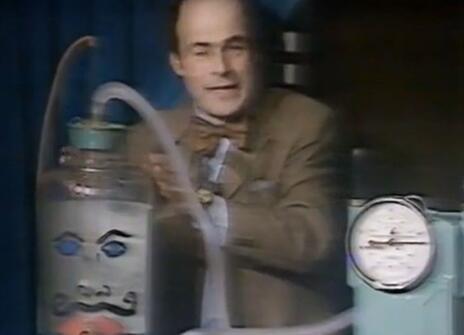 Heinz Wolff standing next to a contraption with a drawn-on face