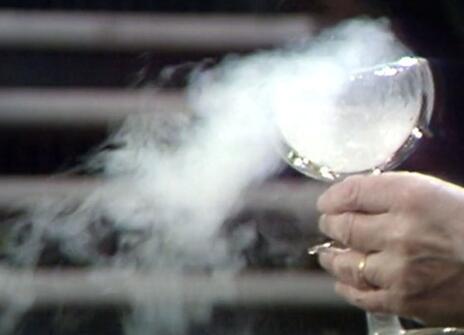 A glass goblet with smoke billowing out from it 