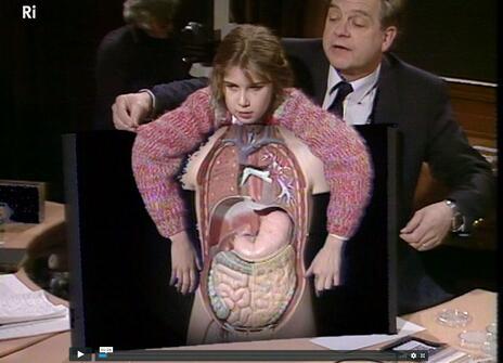 A child standing behind a plastic anatomy model