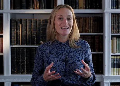Nichola Raihani in a blue blouse mid-sentence with her hands raised in front of her to emphasize a point
