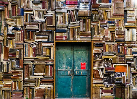 a wall of books and in it a bright teal door