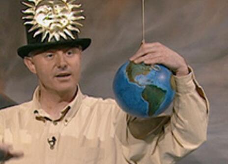 James Jackson wearing a top hat with a sun stitched onto it, holding a small earth globe