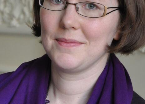 A picture of Harriet Wallace, a white woman wearing glasses and a purple scarf