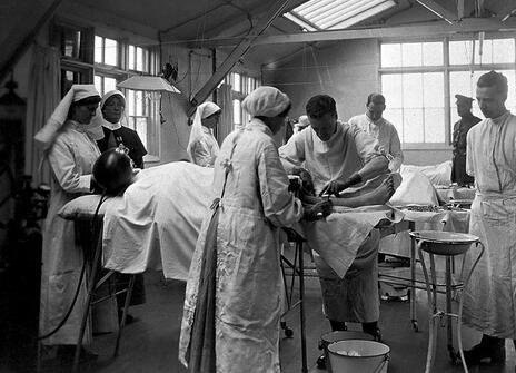 A black and white photo of surgeons and nurses around an operating table