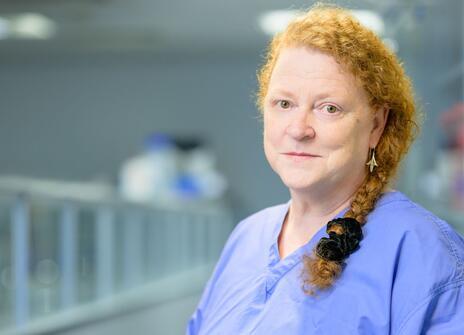 Sue Black, wearing scrubs, stands in a laboratory