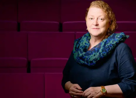 Sue Black, a white woman with curly hair, in front of the Ri Theatre seats