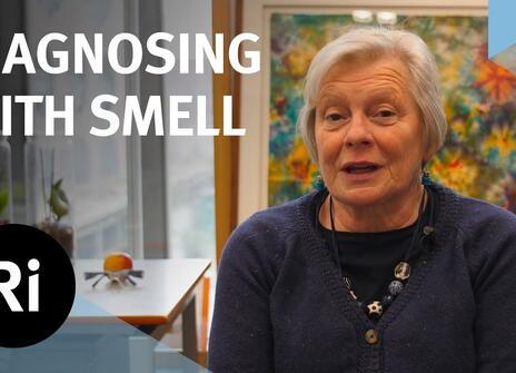 Joy Milne sat in front of a colourful painting