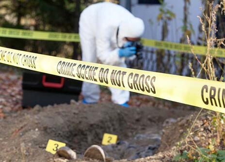 A person on a crime scene, wearing white plastic overalls, taking pictures