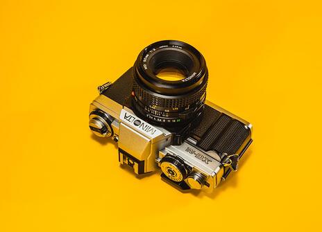 A film camera on a yellow flat backdrop