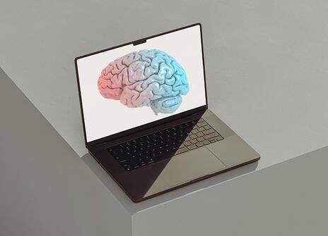 A laptop with a digital illustration of a brain on screen