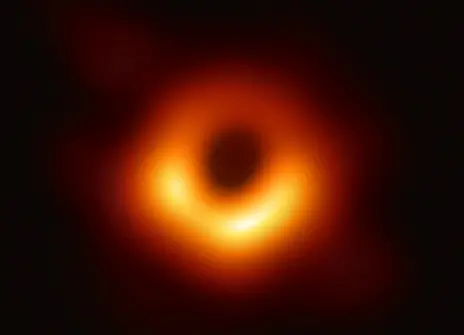 The 2019 Event Horizon Telescope black hole image. Against a dark background, a hollow red and orange circle stands out