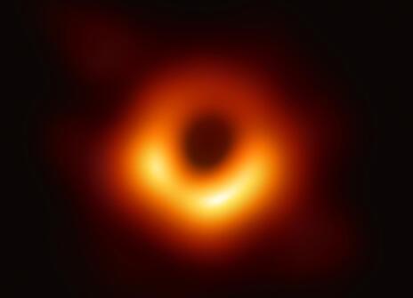The 2019 Event Horizon Telescope black hole image. Against a dark background, a hollow red and orange circle stands out