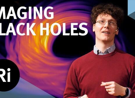 A presenter stands with his hands slightly raised. In the background, there is an illustration of a black hole. The words 'IMAGING BLACK HOLES' are written above, along with the Royal Institution Logo.