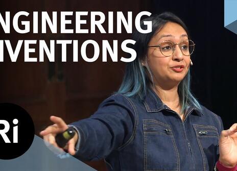 The speaker faces the front of the stage, hands slightly raised. Overlayed are the words 'ENGINEERING INVENTIONS' alongside the Royal Institution's logo.