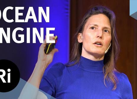 The speaker faces the front of the stage, one hands slightly raised. Overlayed are the words 'OCEAN ENGINE' alongside the Royal Institution's logo.
