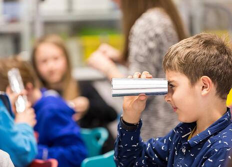 A child looking through a metallic tube