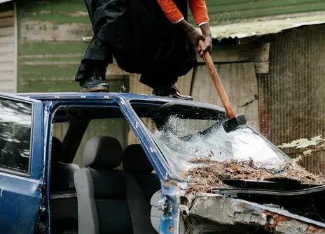Person stood on a car smashing the windshield