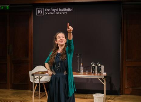 A woman stood pointing upwards in the royal institution theatre