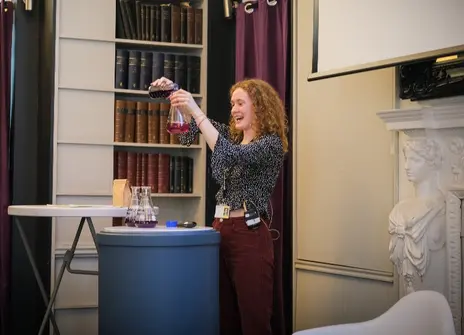 Maya doing a demonstration in the Ri Library, pouring coloured liquid 