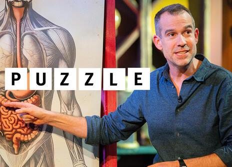 Chris van Tulleken on the set of the Christmas Lectures. The word puzzle is added to the image.