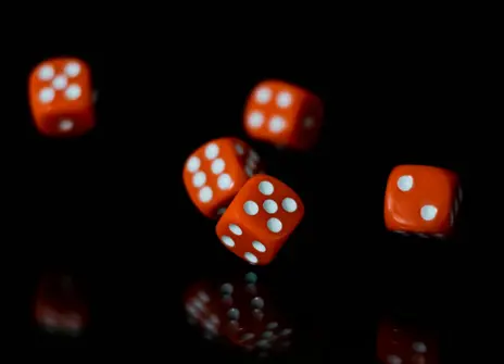 Five dices rolling on a dark background.