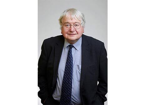 Sir Richard Catlow, he has grey hair, glasses and wears a dark suit with a blue patterned tie 