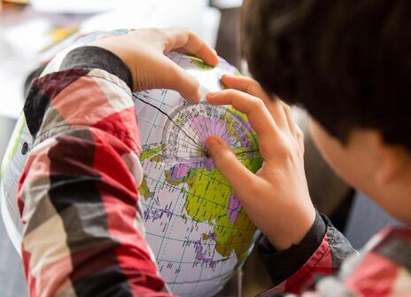 A boy looks at a globe