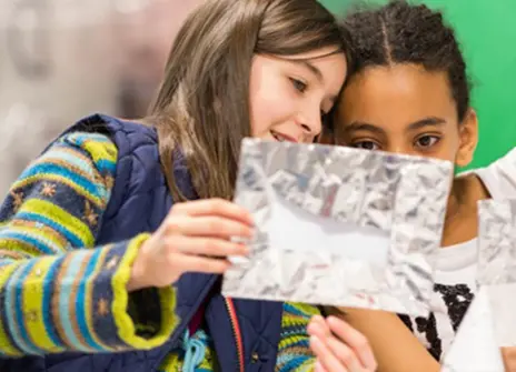 two girls looking at a piece of crumbled up aluminium foil