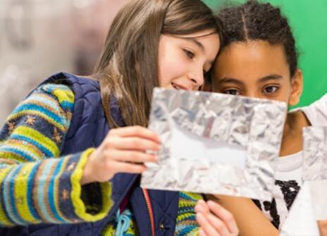 two girls looking at a piece of crumbled up aluminium foil
