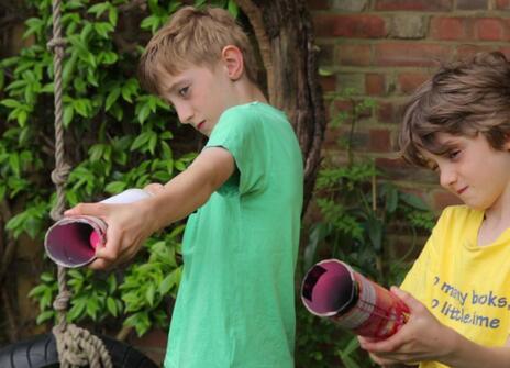 two boys holding up Pringles cans as if they are cannons