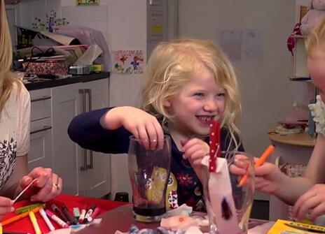 a woman and two toung girls laughing and doing a science experiment with felt tip pens, kitchen paper and water