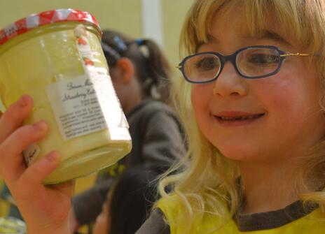 a young girl with glasses is looking at a jar of cream