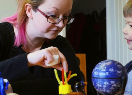 a woman and a small boy are looking at a selection of toys on the table
